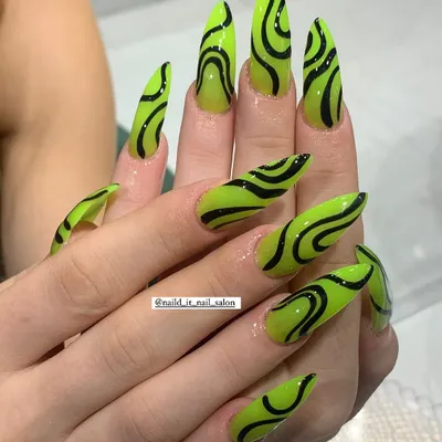 The ultimate bold look. Extra-long stiletto nails in a shocking neon green are covered in hand-painted black abstract swirls for a high-impact, graphic effect.