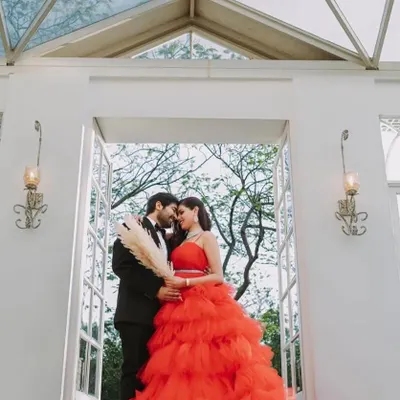A romantic close-up of a couple, with the bride-to-be in a stunning red ruffled gown. This dress is a favorite for pre-wedding photoshoots because of its vibrant color and texture.