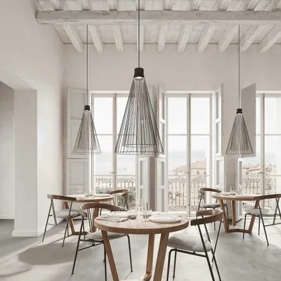 The Ikonika pendant by Karman, with its airy metal cage, brings a light, graphic element to this charming restaurant interior. The design is suitable for both indoor and outdoor use, offering incredible versatility for hospitality projects.