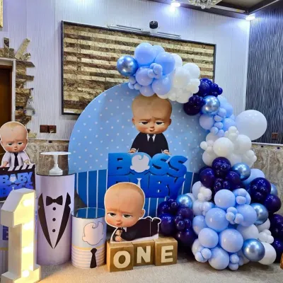 A complete Boss Baby theme for a first birthday, featuring multiple character cutouts, a custom backdrop, "ONE" blocks, and a light-up marquee number.