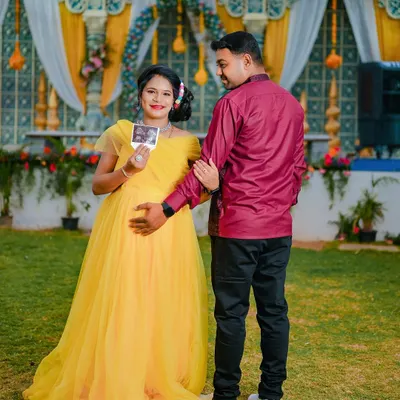 An outdoor maternity shoot celebrating the upcoming arrival. This couple wanted to announce their joy with cute props like baby shoes and their ultrasound picture, set against a beautiful event backdrop.