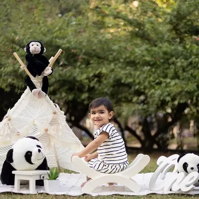 An outdoor first birthday shoot with a cute panda and teepee theme. The natural greenery provides a beautiful backdrop.