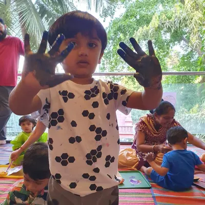 The sign of a great art session: messy hands! This little boy is showing off his paint-covered hands with a proud look. I encourage kids to get fully immersed in the creative process.