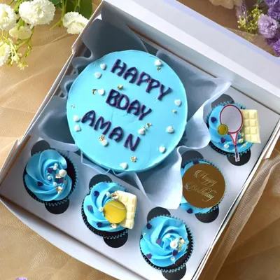 A tennis-themed bento box I made for a birthday. The set features a light blue mini cake and matching cupcakes decorated with edible tennis balls, rackets, and white chocolate bars.