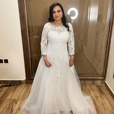 The quintessential Christian bride. This full-length view shows the bride in her beautiful lace and tulle gown. Her makeup is soft and natural, and her hair is styled elegantly to complete the look.