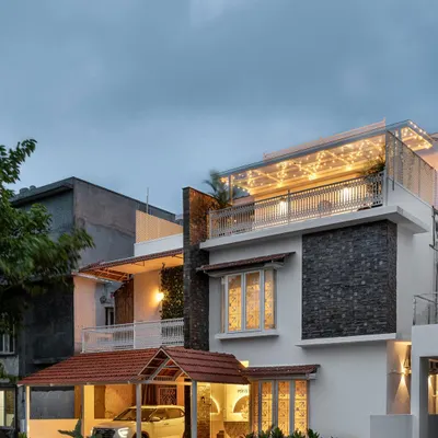 The exterior of 'Mina Nivas' is a beautiful blend of styles. The stone cladding, traditional sloping roof, and white picket fence create a charming and inviting facade that hints at the colonial-inspired interiors within.