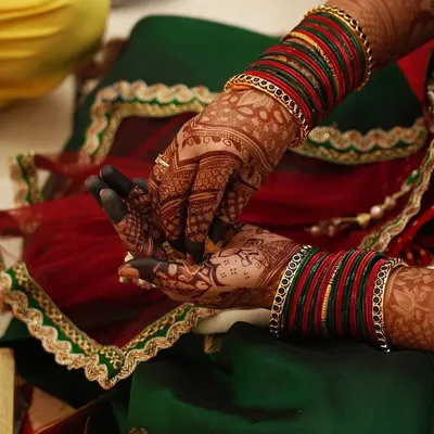 The beautiful final stain of our mehndi, set against a festive green and red outfit. The deep color highlights every intricate detail of the design on the hands and wrists.