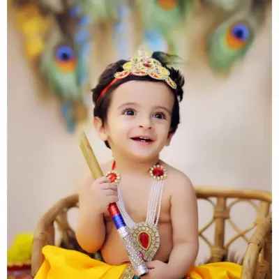 A joyful portrait from our popular Krishna-themed photoshoot. We use colorful backdrops with peacock feathers and provide detailed costumes to bring the story of little Krishna to life.