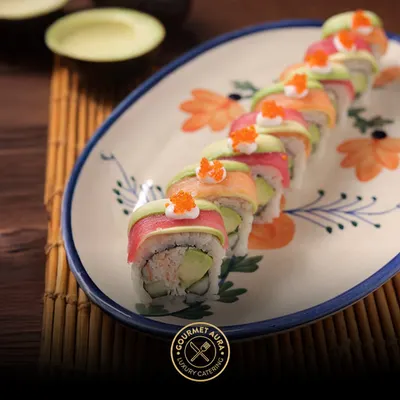 A vibrant rainbow roll, showcasing layers of fresh tuna, salmon, and avocado, topped with bright orange tobiko. This is a perfect example of our commitment to both flavor and visual artistry in our sushi offerings.