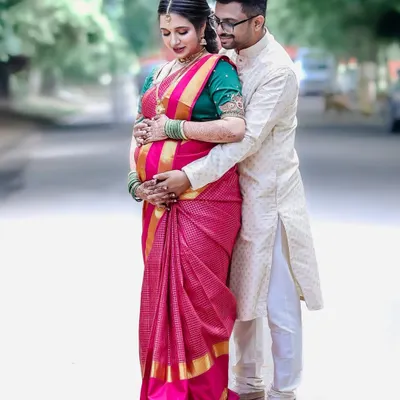 A classic pose celebrating the journey to parenthood, set against the backdrop of a traditional baby shower ceremony. The embrace signifies support and shared excitement.