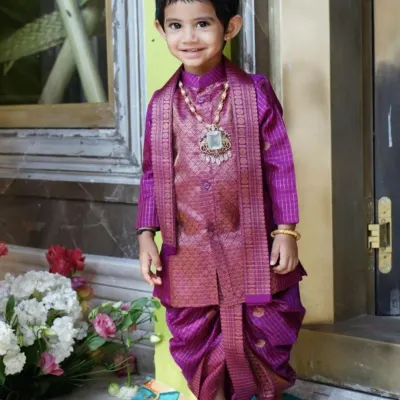This little one is ready for a celebration in a custom-designed silk dhoti kurta set. I crafted this piece in a rich magenta, complete with a matching brocade vest and a traditional shaila, ensuring he looks like royalty while staying comfortable enough to play. It's a perfect example of traditional South Indian kids' ethnic wear.