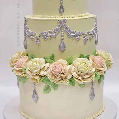 An elegant three-tiered engagement cake decorated entirely with buttercream. The focus is on the hand-piped pastel roses and delicate silver scrollwork, techniques I cover in my advanced buttercream class.