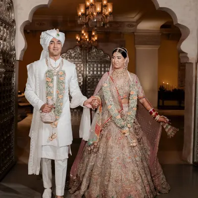 A royal union deserves a regal setting. Here, the couple walks hand in hand through the magnificent archways of a Jaipur palace, their traditional attire complementing the grandeur of their surroundings. This is a portrait of heritage and love intertwined.