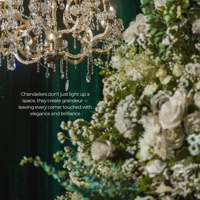 A classic crystal chandelier paired with lush white florals against a deep green velvet backdrop. This combination creates a sense of timeless grandeur and sophistication, ideal for a luxury event or gala.
