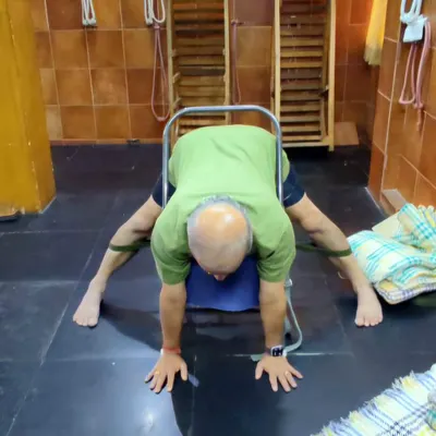 A wide-legged forward bend using a chair for support.