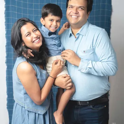 A perfect family hug. The coordinated denim and blue outfits look wonderful against the simple backdrop, and their bright, happy smiles are absolutely infectious.