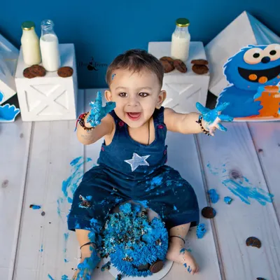The pure joy of a cake smash! This little Cookie Monster is having the best time, with blue frosting on his hands and a huge smile on his face.