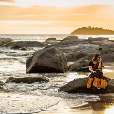 A breathtaking sunset at a rocky beach in Mangalore provides the perfect canvas for a dramatic and romantic pre-wedding portrait.