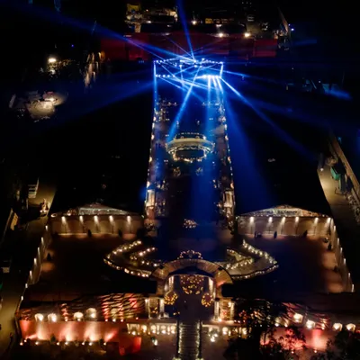 An incredible aerial shot of 'The Lost City' at night, showcasing the massive scale of the production. The dramatic blue lighting on the main stage creates a powerful focal point in this imagined world.