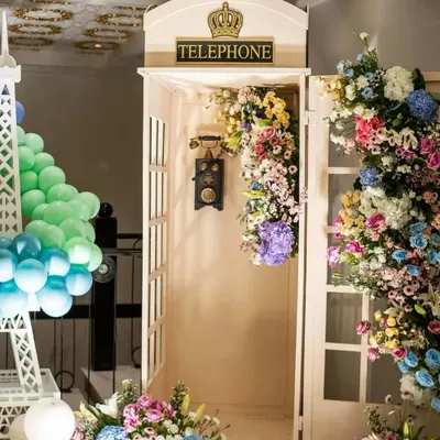 A classic British telephone booth overflowing with a cascade of colorful flowers. This prop, next to a miniature Eiffel Tower, adds an element of surprise and charm to our Parisian theme.