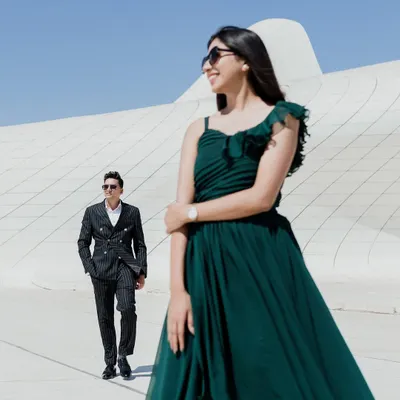 A candid moment of joy against the futuristic curves of the Heydar Aliyev Center in Baku. The contrast between her flowing green dress and the stark white architecture creates a visually stunning pre-wedding portrait.