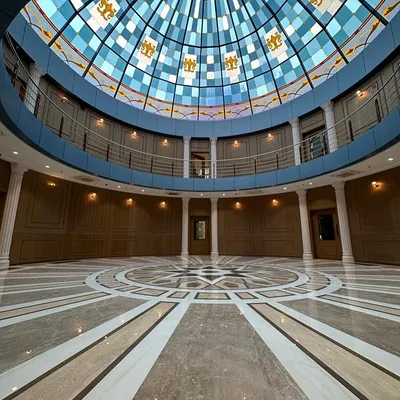 The completed grand lobby of the Arihant Aspire clubhouse, featuring Mumbai's largest glass dome. The intricate marble flooring and wood-paneled walls create a sense of timeless elegance and scale.