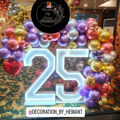 A close-up of the large, illuminated "25" marquee numbers used for a silver jubilee anniversary. The numbers are the centerpiece, surrounded by a lush arch of metallic purple, red, and gold balloons.