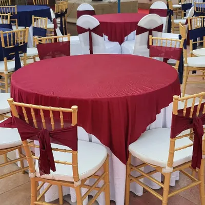 We provide elegant seating arrangements that match your event's color scheme. Here, round tables are dressed in maroon and white linens, with matching sashes on the classic gold Chiavari chairs.