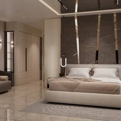 A luxurious master bedroom where comfort meets high-end design. The space includes a plush upholstered bed, a full seating area, and a striking feature wall with marble panels and metallic accents.