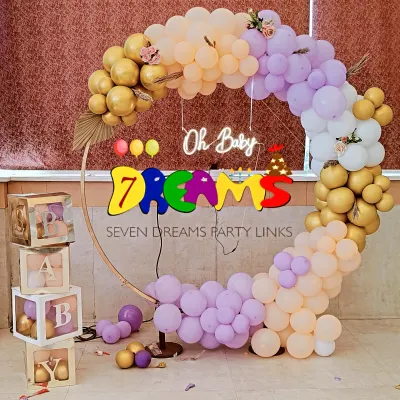 This is a popular modern baby shower design. I use a circular gold-tone ring, an organic arch of pastel and metallic balloons, and a custom "Oh Baby" neon sign. The transparent "BABY" blocks can be filled with balloons matching your color scheme.