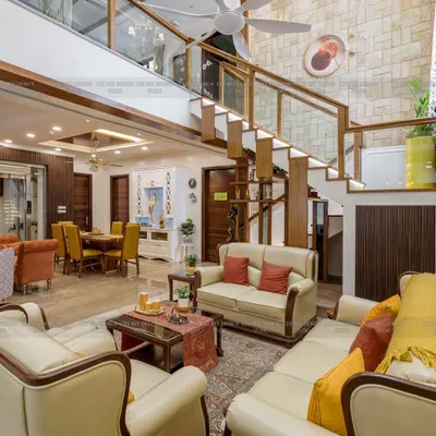 A grand, double-height living space in a penthouse, with a prominent staircase featuring a glass railing and stone-clad wall.