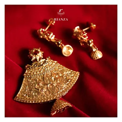 This temple jewellery pendant and earring set showcases traditional gold embossing work. The intricate floral and paisley motifs give a new dimension to ethnic wear with a touch of modern elegance.