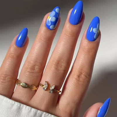 A vibrant and playful design featuring hand-painted daisies on a bold blue base. This look on almond-shaped nails shows our ability to create fun, floral nail art that pops with color.