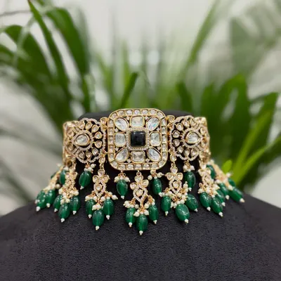 This is a classic Kundan choker with a central black stone and emerald green bead drops. It's a versatile rental piece that pairs well with many traditional outfits.