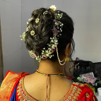 A detailed view of a beautiful, textured bridal bun. I use fresh flowers and delicate accessories to create hairstyles that are both romantic and secure.