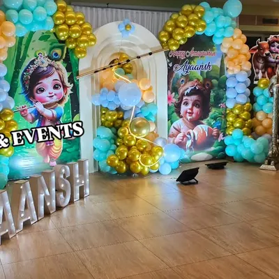Another angle of the Little Krishna naming ceremony, showing how the balloon columns and character cutouts frame the main stage. The light-up marquee letters add a beautiful glow to the entire setup.