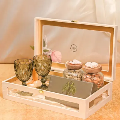 This sophisticated Rakhi hamper is perfect for a sibling with refined taste. It features two elegant wine glasses, jars of premium nuts, and a personalized card, all presented in a beautiful wooden keepsake box.
