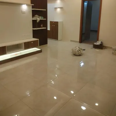 A spacious living room after a fresh coat of paint. The walls are finished in a warm, neutral off-white, creating a bright and airy feel. Notice the clean lines and glossy tiled floor, which we carefully protected during our work.