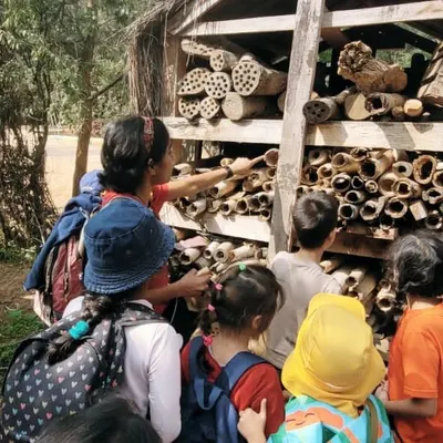 Children get a close-up look at a large insect hotel at Kadugodi Tree Park, examining the different materials used to create habitats for various insects.