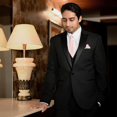 A classic portrait of the groom looking sharp in his black tuxedo at the Noor Mahal Palace. The warm, ambient lighting creates a sophisticated and timeless look.