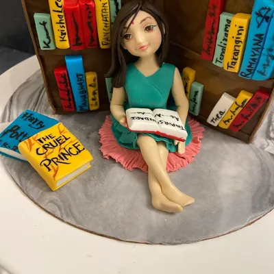 I made this cake for a young book lover. The figurine is personalized to capture her likeness, surrounded by tiny, edible versions of her favorite books.