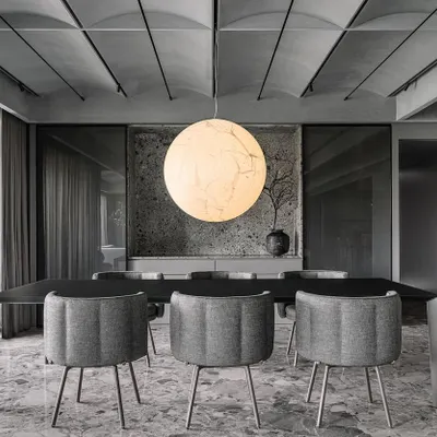 The 'Moon' pendant by Davide Groppi serves as the central anchor in the Vaulted Haus dining area. Its large, spherical form provides a soft, diffused light that holds the entire monochromatic space together under the vaulted ceiling.