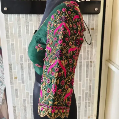 A side view showcasing the incredibly dense embroidery on the sleeve of this emerald green blouse. The vibrant pink and gold threads create a stunning contrast against the dark fabric.