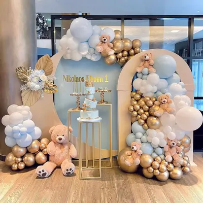 A sophisticated and modern teddy bear theme using a neutral color palette. This setup features arched backdrops, beautiful balloon clouds in blue, white, and gold, and elegant cake stands.