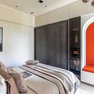 This kids' room is a world of wonder. The design includes a cozy bed, a playful reading nook in a vibrant orange arch, and a sleek wardrobe, creating a space where creativity knows no bounds.