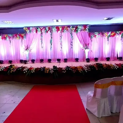 A classic stage decoration I created for a wedding reception. The design features a backdrop of soft pink drapery, accented with floral arrangements and illuminated by professional uplighting.