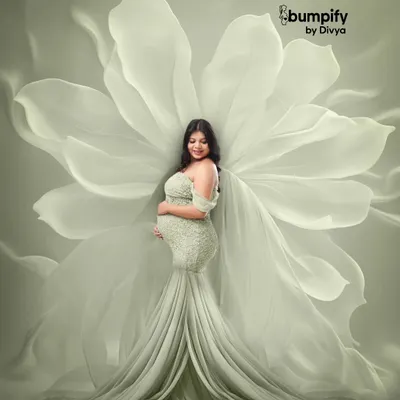 A truly angelic portrait of a mom-to-be in a light green gown, with a backdrop of giant, ethereal white flower petals that look like wings. This is one of my most popular fine art maternity setups.