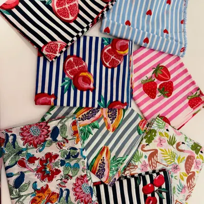 A vibrant collection of our printed fabrics. We offer a wide variety of patterns, from bold stripes with pomegranates to sweet strawberries and florals, ready to be transformed into your child's next favorite outfit.