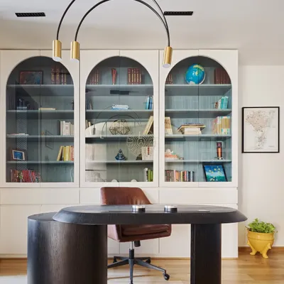 A home office should be both practical and calm. For this duplex in Lower Parel, we designed a functional workspace with a custom dark wood desk, arched sliding doors, and a built-in bookshelf that pulls the entire room together.