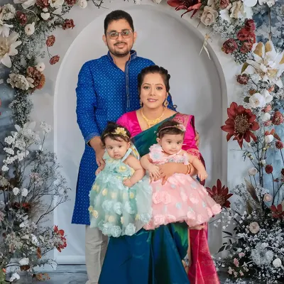 A lovely family portrait with their twin toddler girls. Dressed in beautiful traditional and party wear, the family is framed by a stunning floral arch, creating an elegant and memorable photograph.